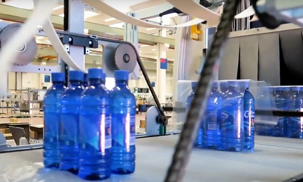 Bottles on an assembly line getting wrapping.